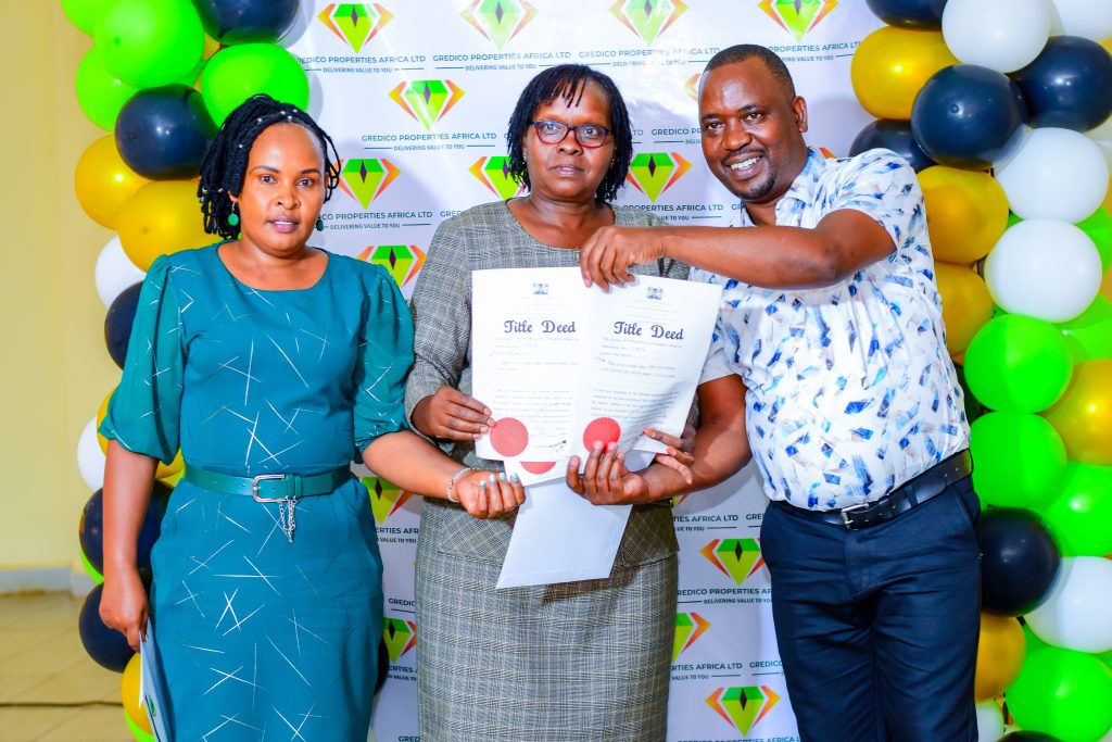 Happy landowner receiving her freshly issued ready title deeds at Gredico Properties title issuance event.