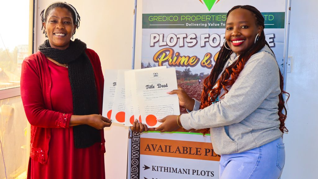 Happy buyer receiving her individual title deed at Gredico Properties after payment completion